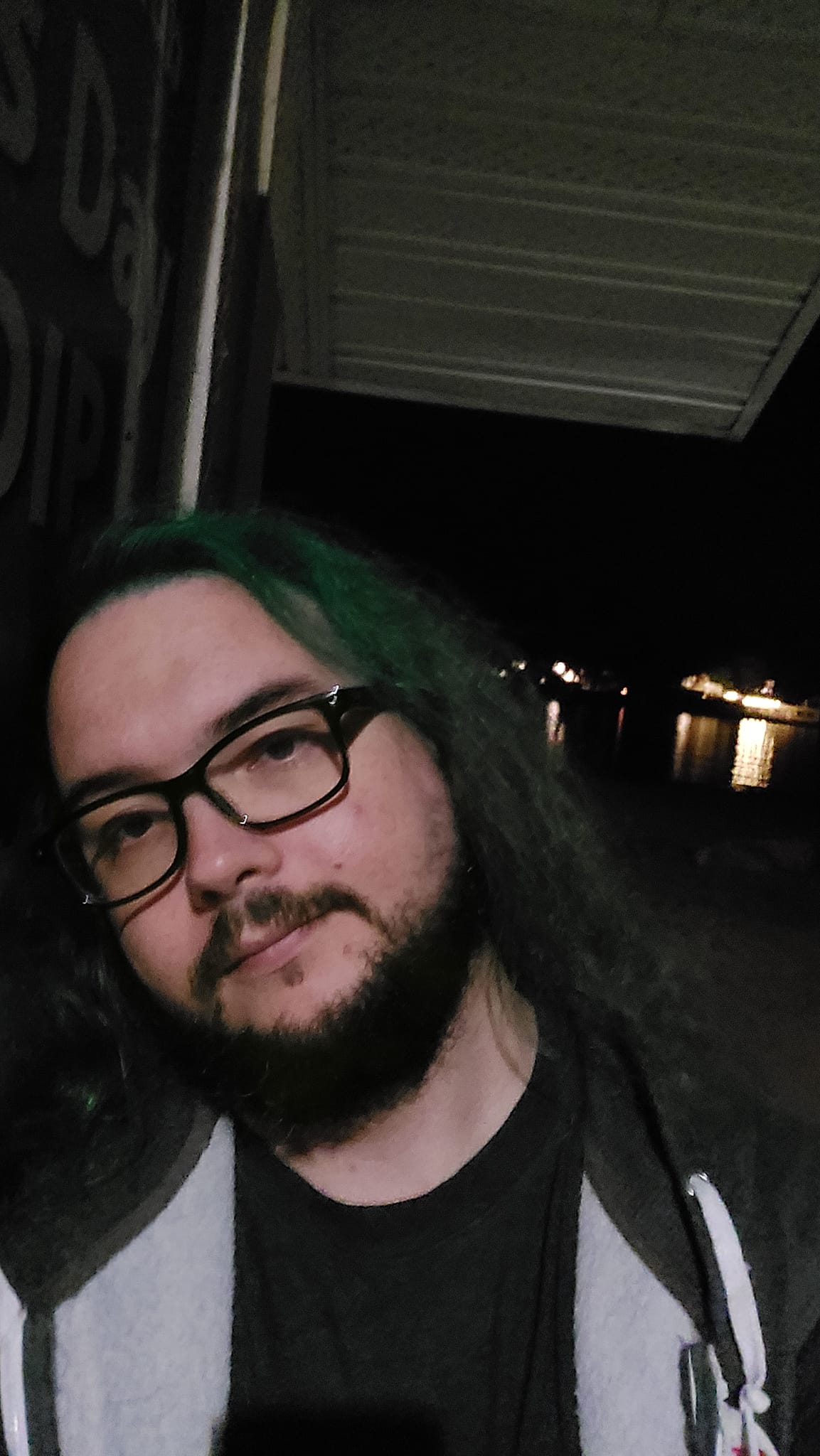 A man with green hair is at the beach after dark, photo 1